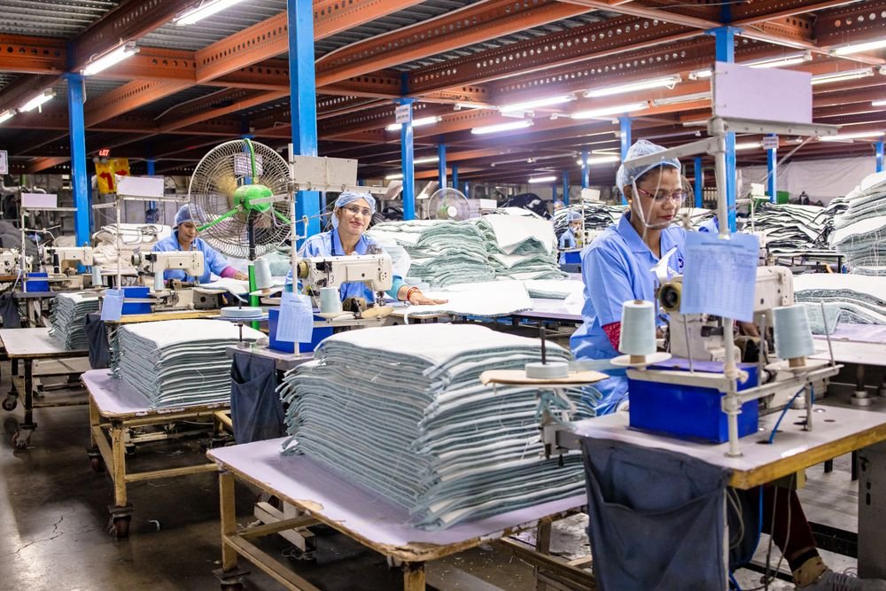 Workers at sewing machines organising fabric on an apparel production floor