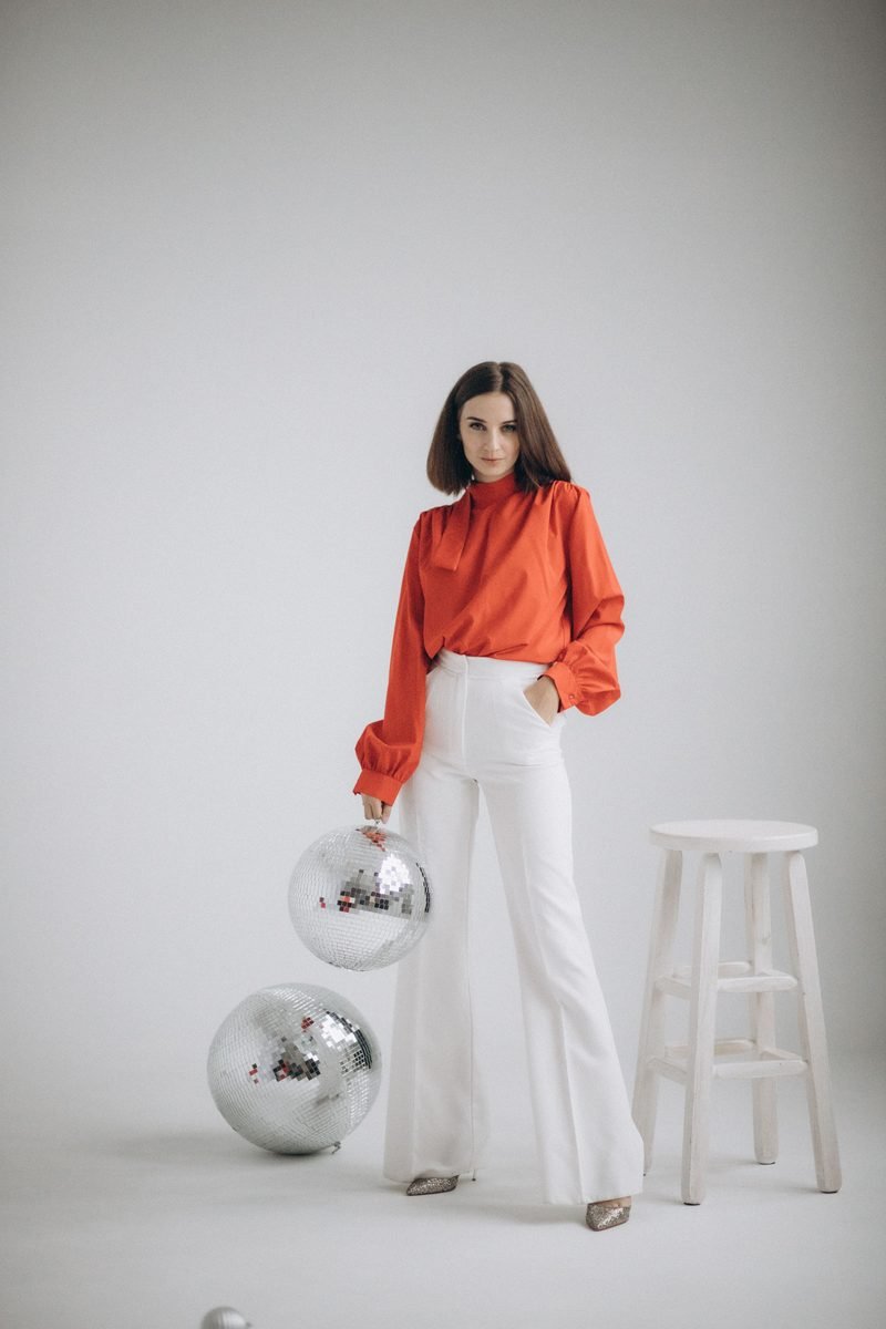 A loose orange blouse worn with wide white trousers